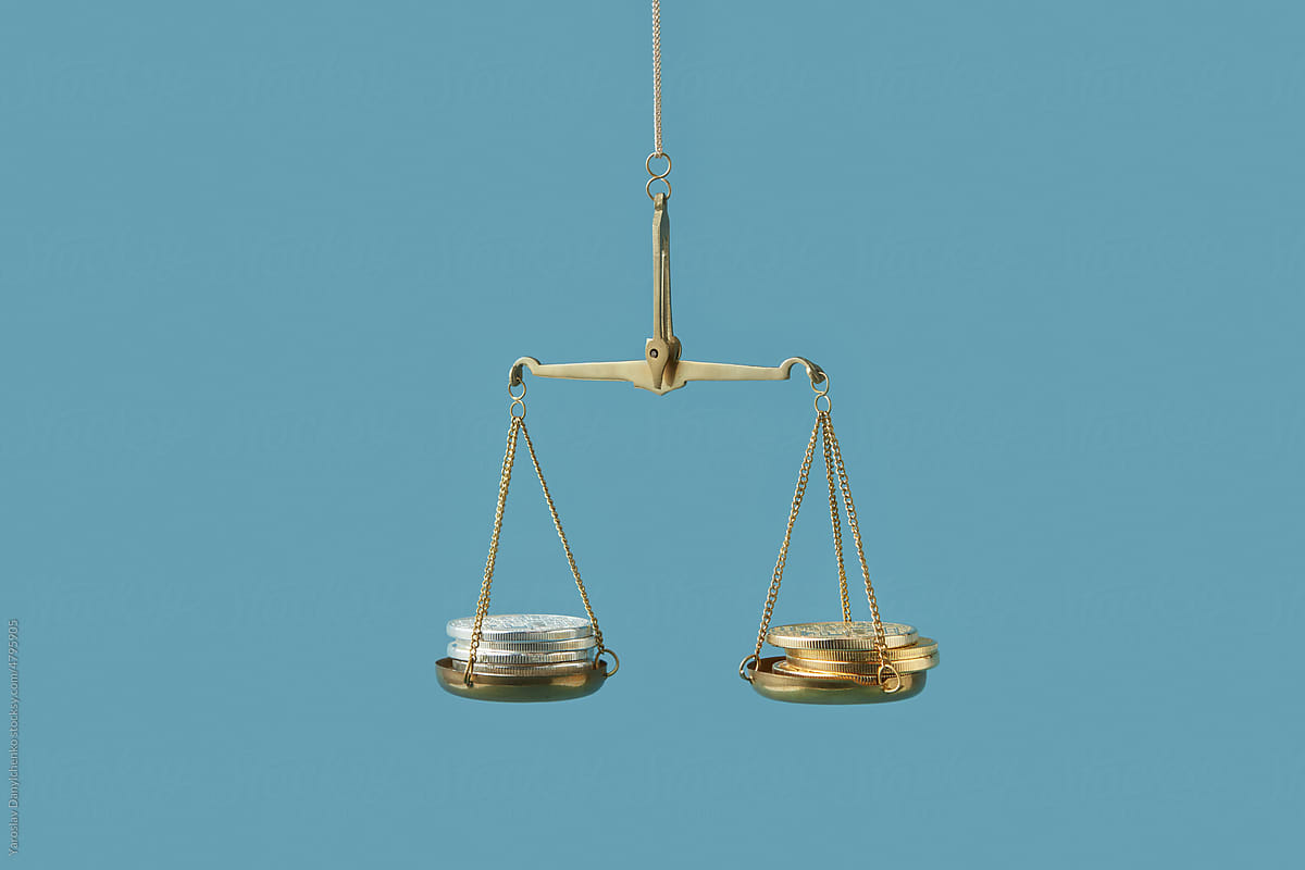 Silver and golden coins on justice scales.