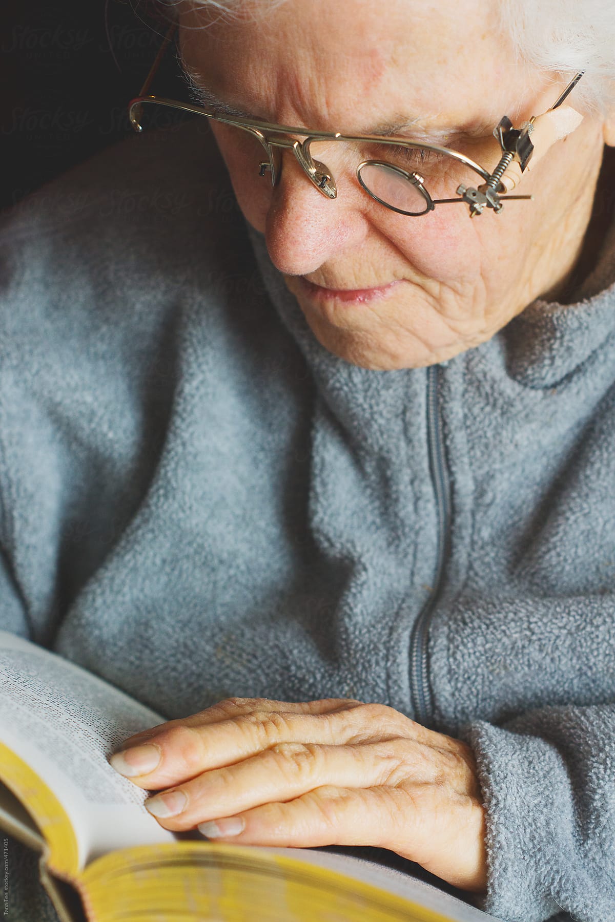 Older woman wearing homemade glasses to read