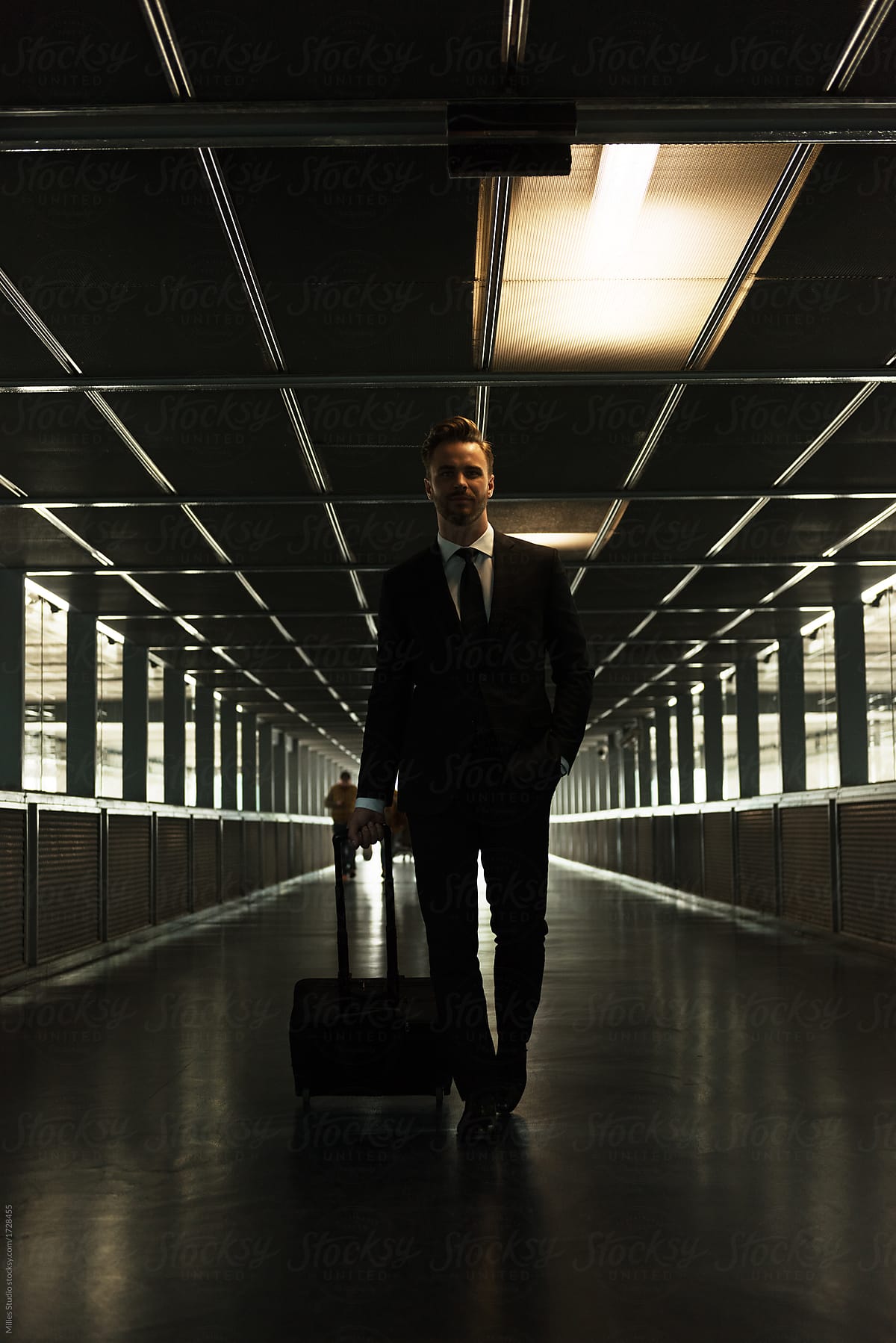Confident man with suitcase in dark hall