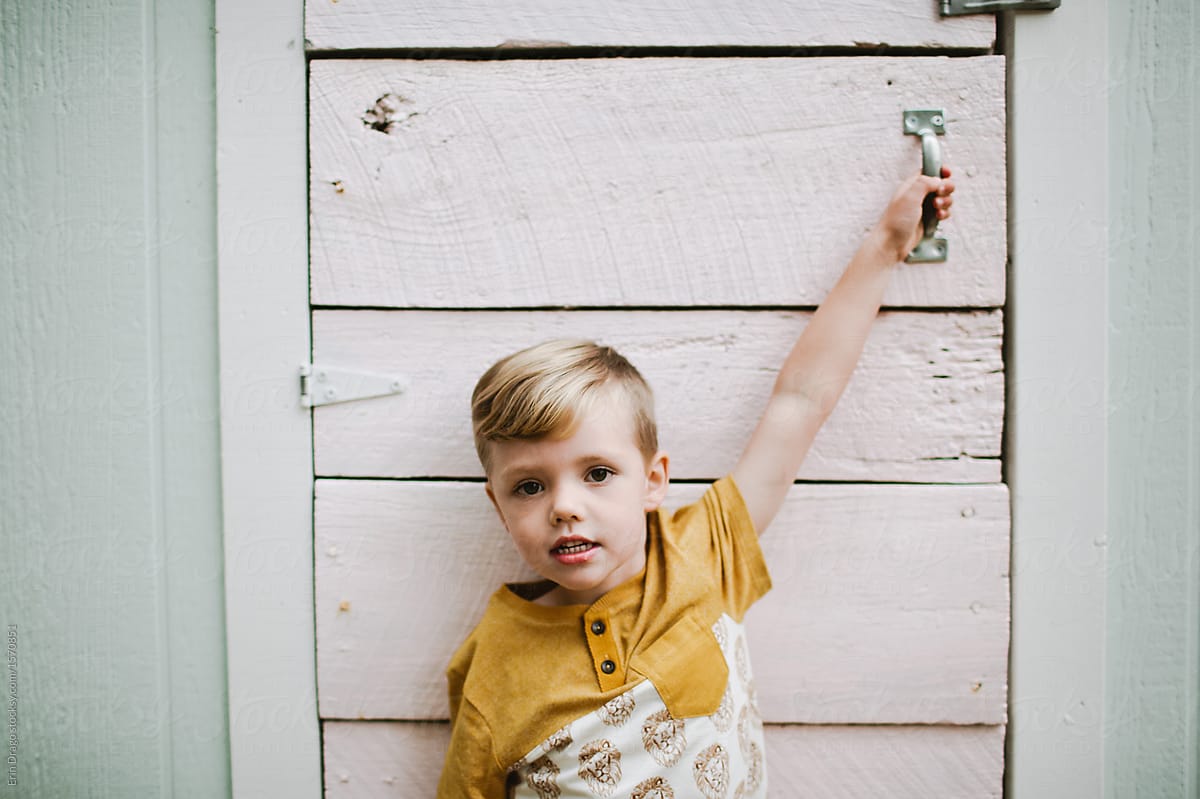 Little boy holding the handle of a door
