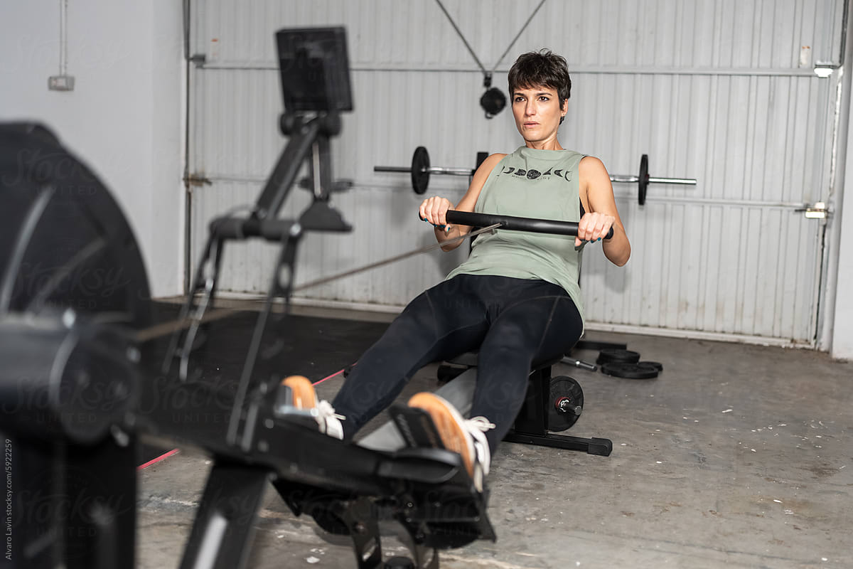 Woman Exercising on Rowing Machine in Home Gym