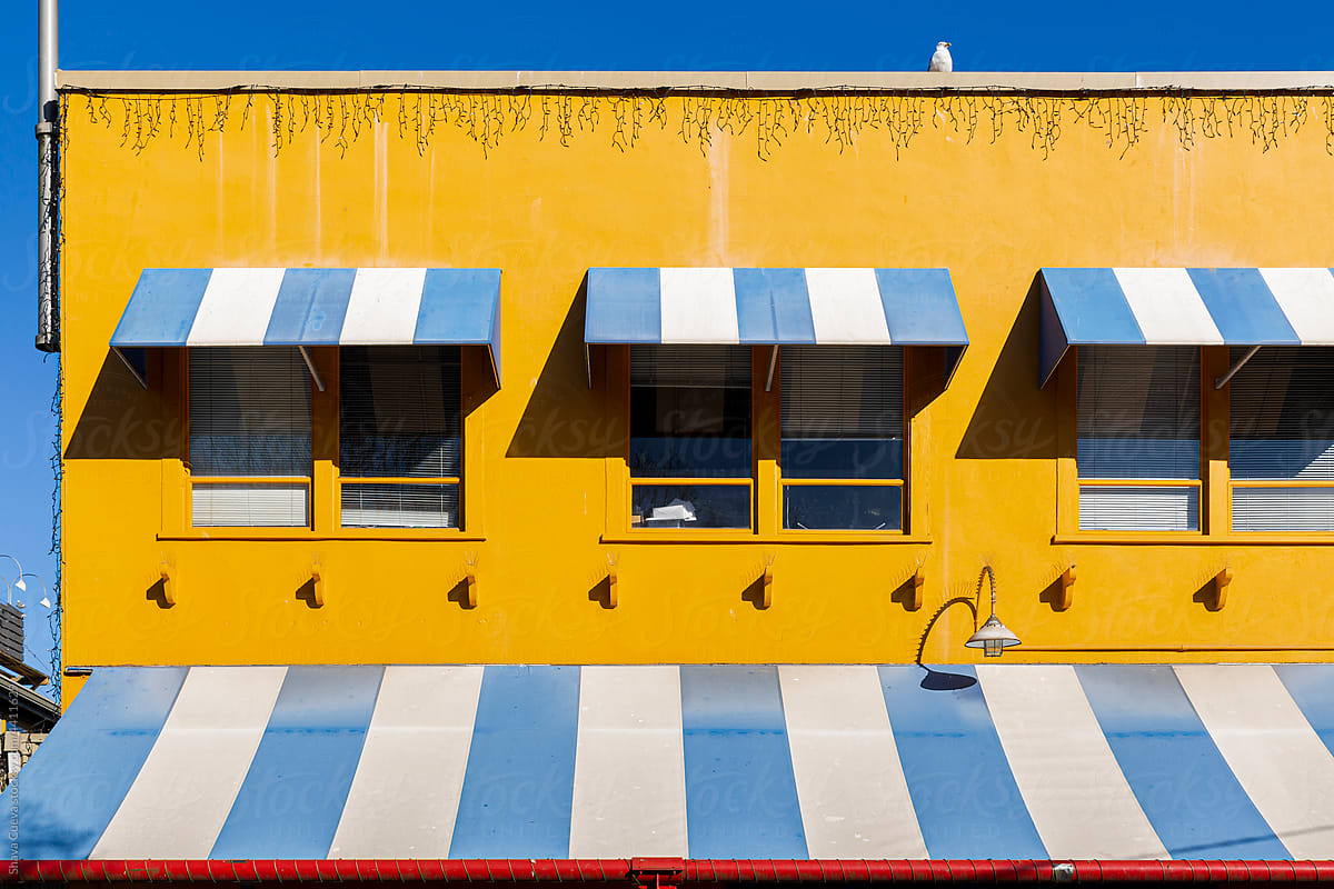 A yellow facade with blue and white awnings