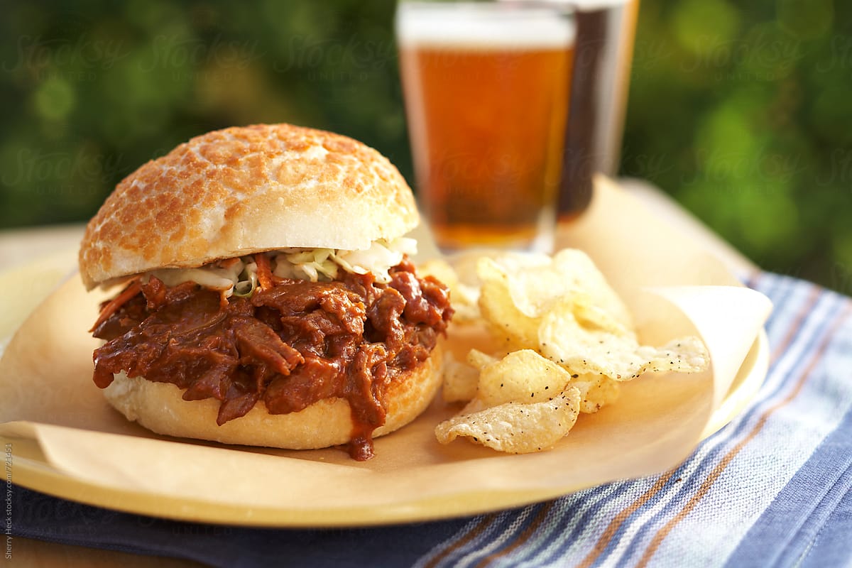 BBQ pulled pork on bun with potato chips and beers
