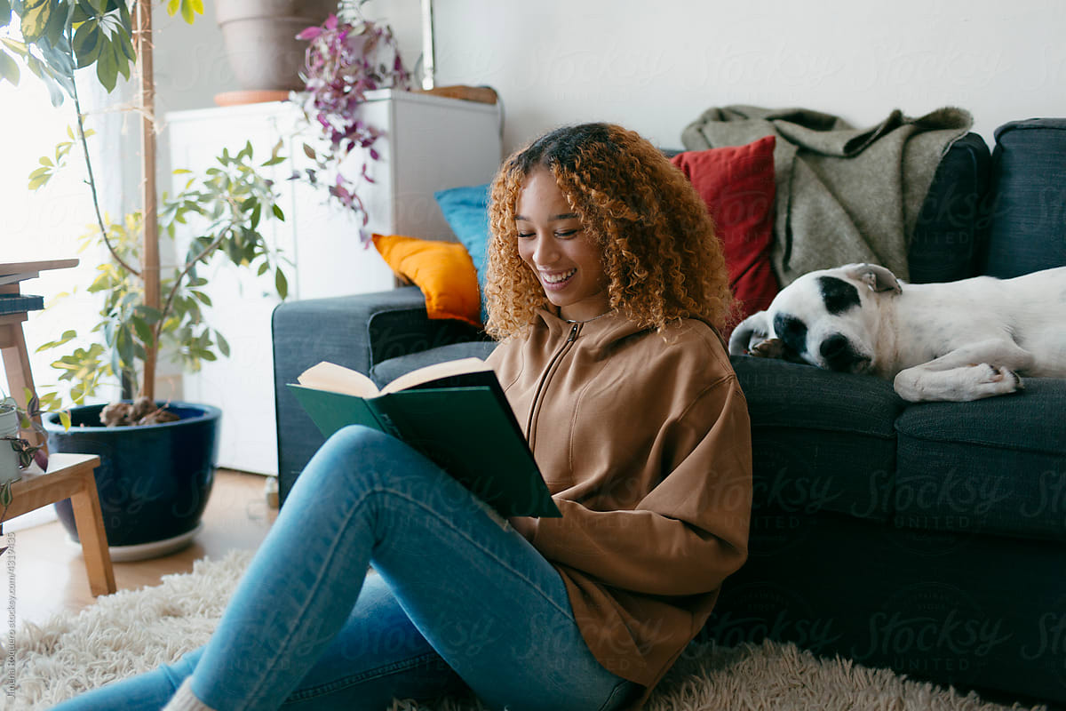 Young happy woman reading at home living room with dog