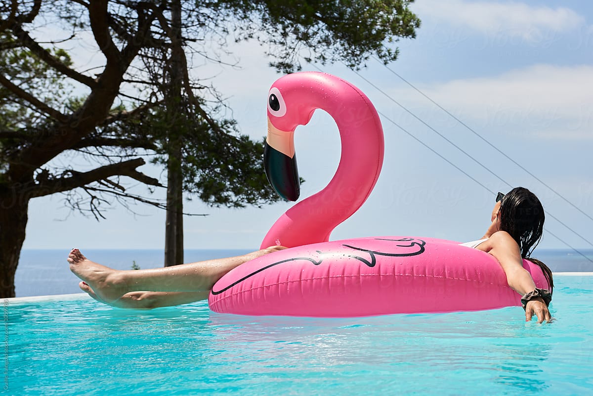 Brunette on flamingo air mattress at pool