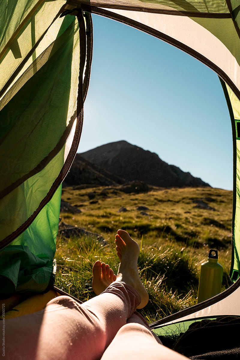 View from inside a camping tent with legs going outside