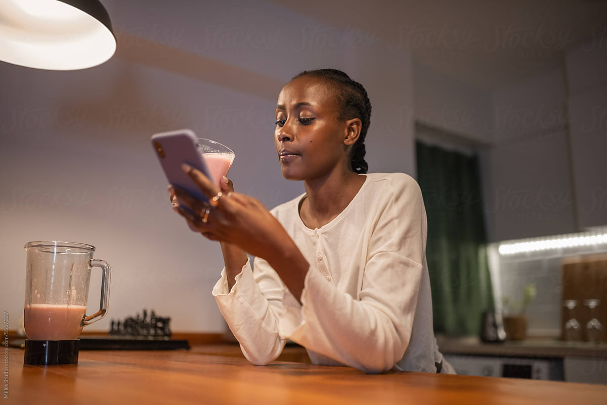 Black female browsing cellphone and drinking milkshake