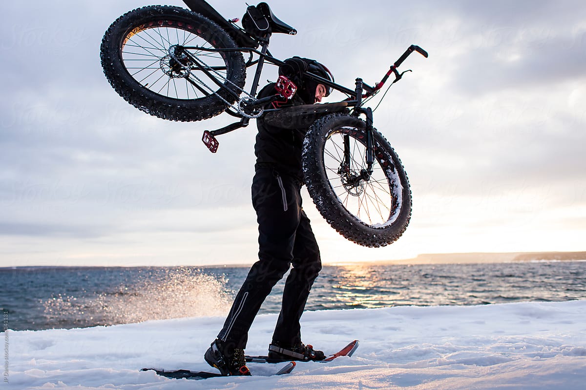 Extreme Winter Sport Man With Snowshoes Carrying Fat Bike in Snow