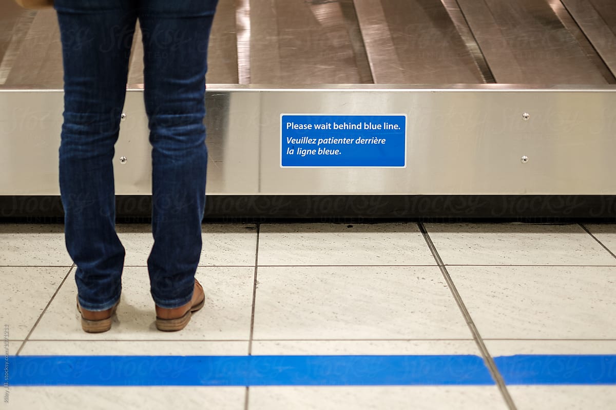 An anonymous person stands in front of a blue line contrary to signage