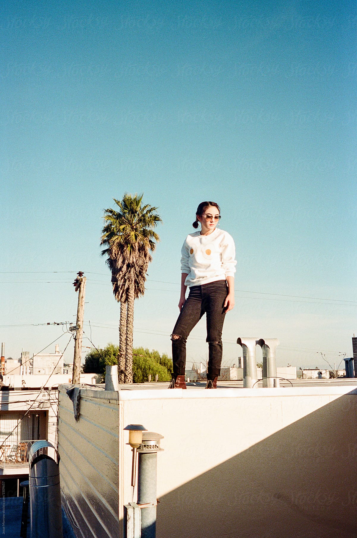 young woman wearing egg sweat shirt sitting on roof top in city