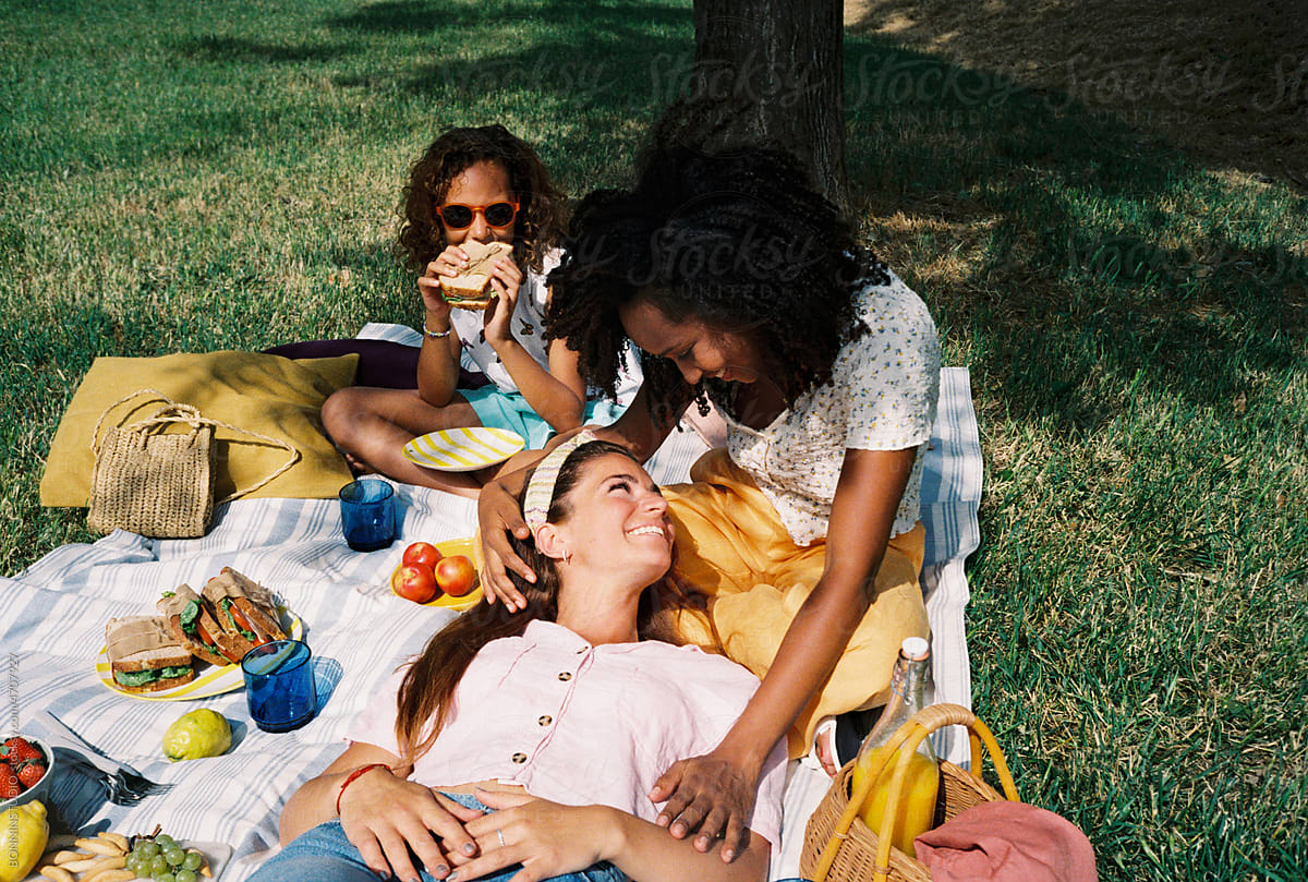 Multiethnic lesbian couple with their daughter enjoying picnic