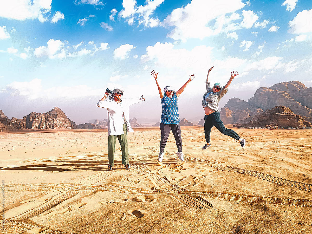 Three middle aged women executing jump shot in the desert.