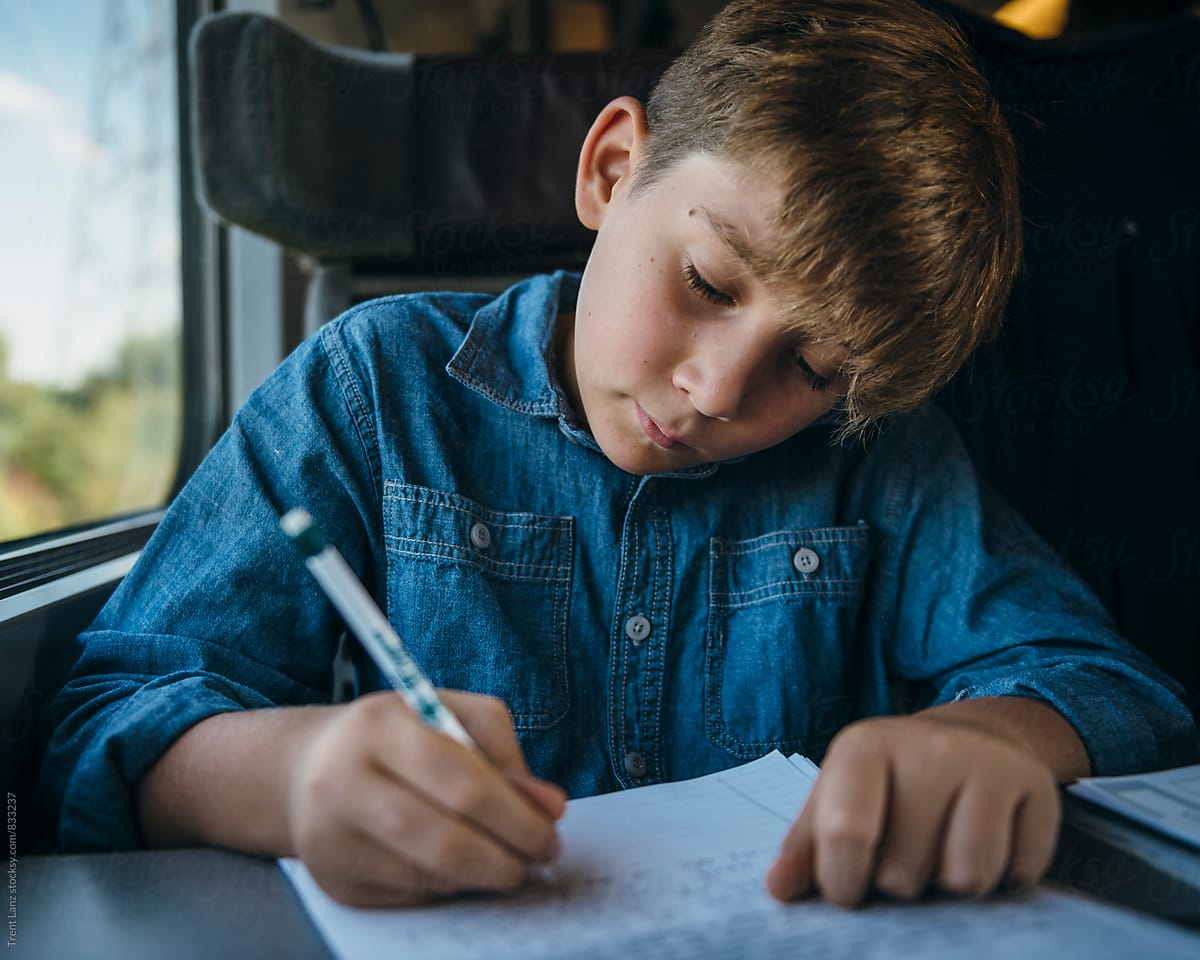 Young boy writing a letter while travelling in train