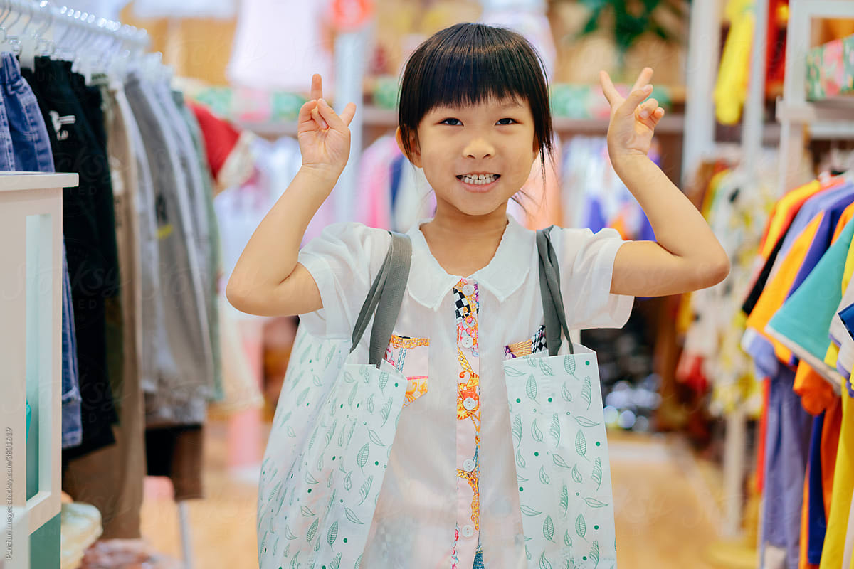 Little girl holding shopping bags in clothing store