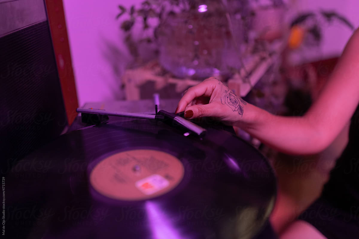 Close-up of female hand putting on a vinyl player