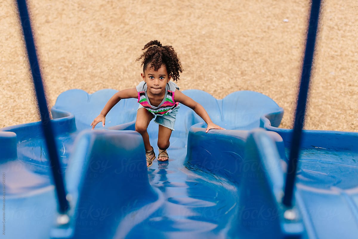 A little girl climbing up the slide at the playground