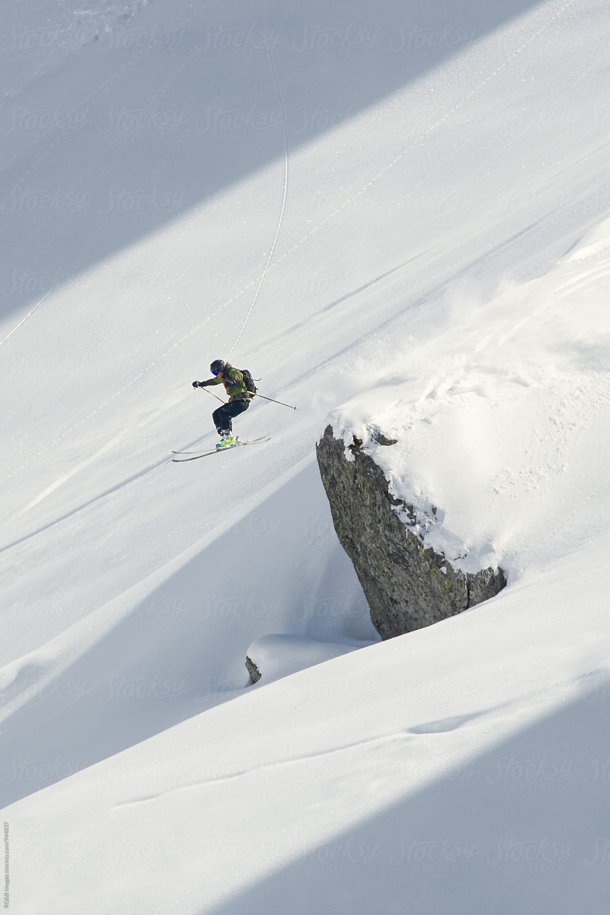 Skier jumping off a snow covered rock