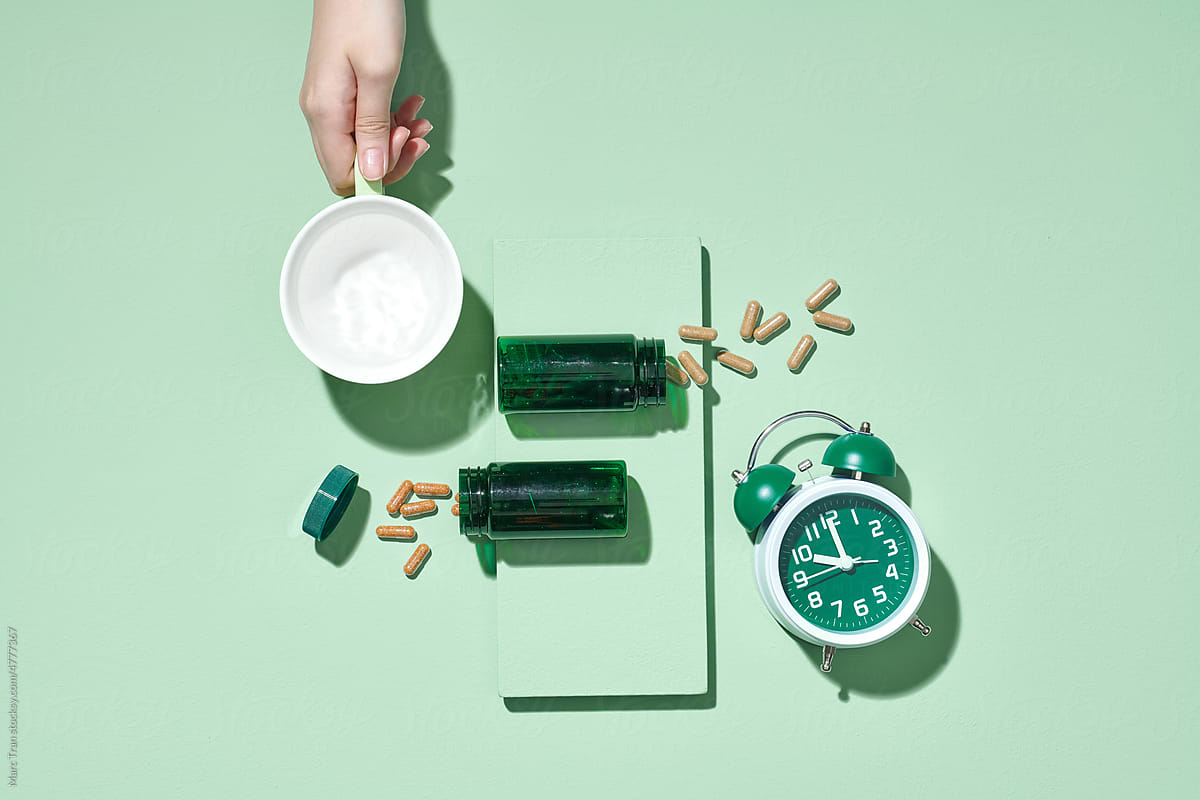 Pills, bottles and a glass of water on a light green background.