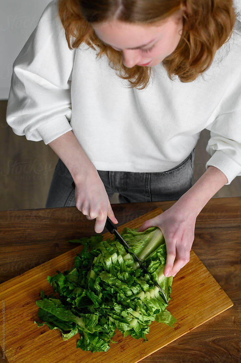 Woman chopping lettuce at the kitchen