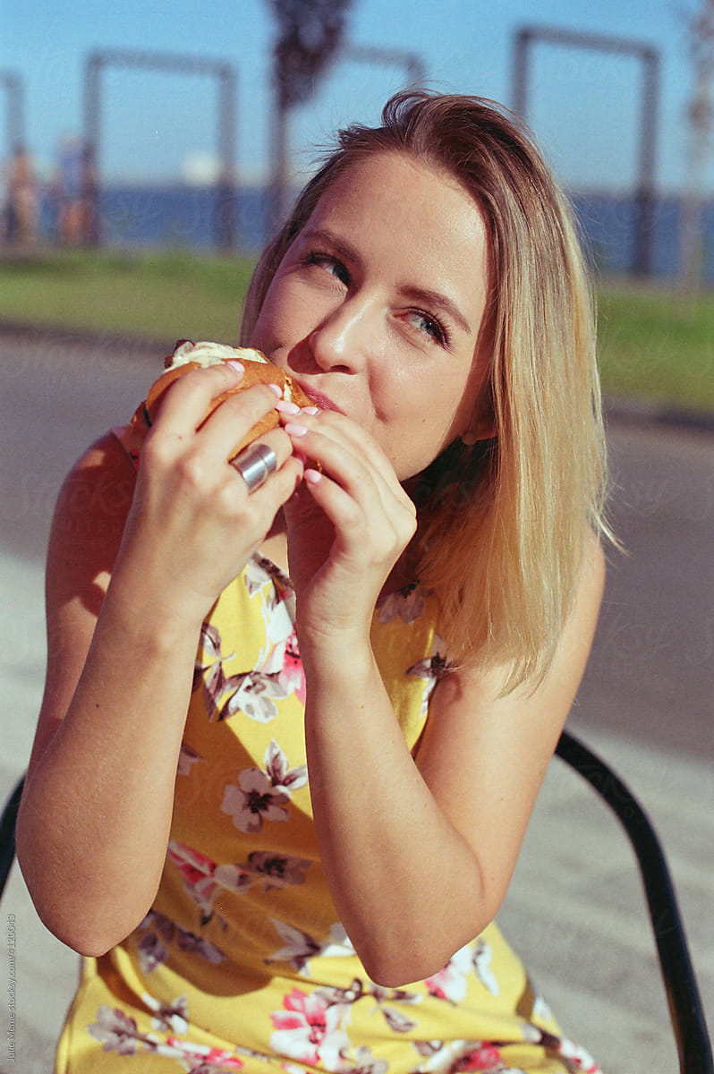 Blond girl eats hot-dog on the sunny day
