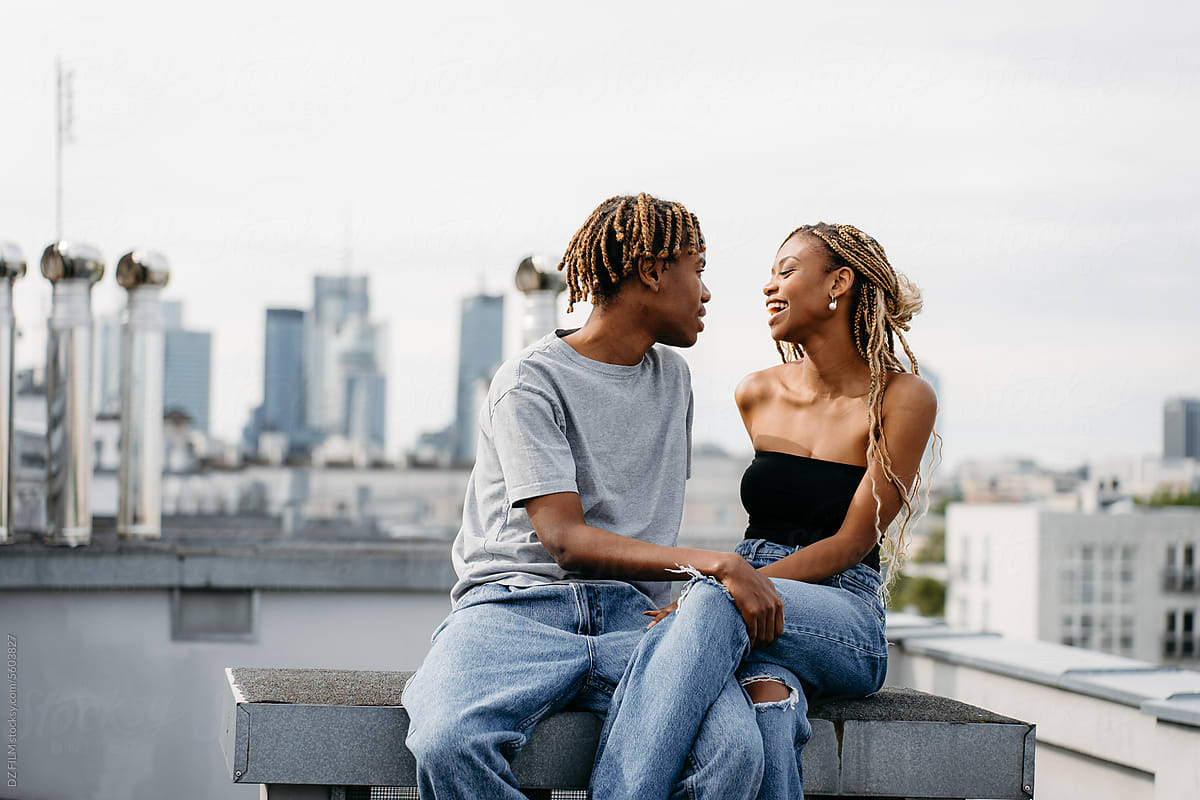 A man and a woman are sitting on the roof of a city building