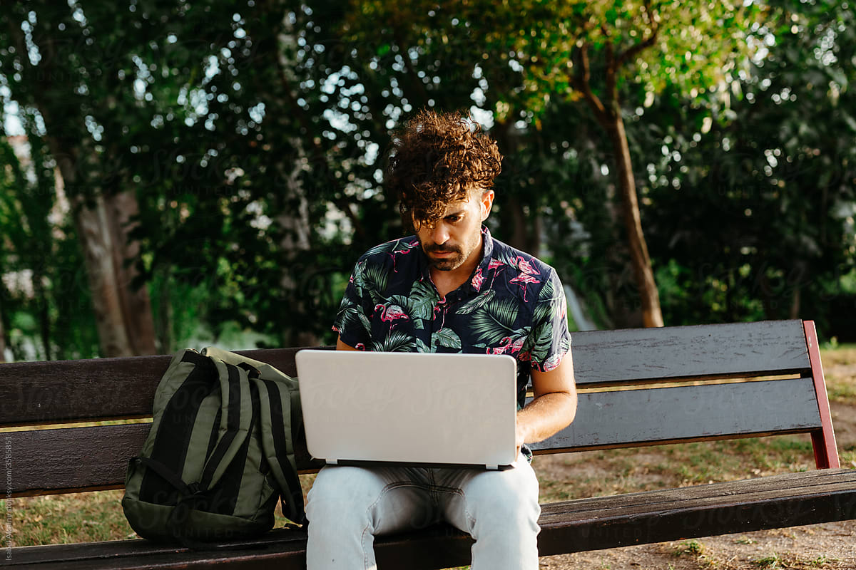Portrait of a young boy on a park bench with his computer and backpack