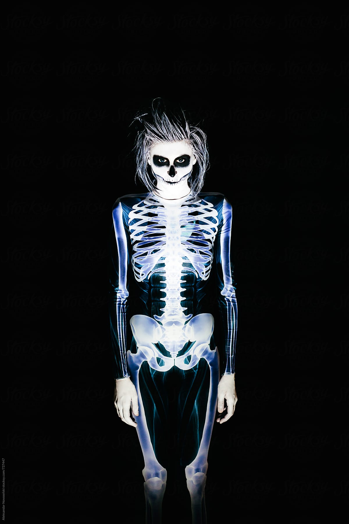 Spooky portrait of woman in skeleton costume and halloween make up on black background
