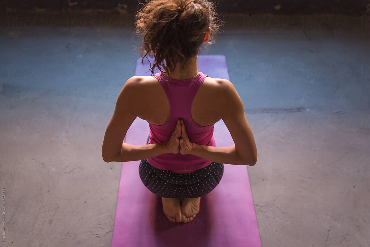 Rear view of fitness woman doing yoga in reverse prayer pose. Pashchima Namaskarasana