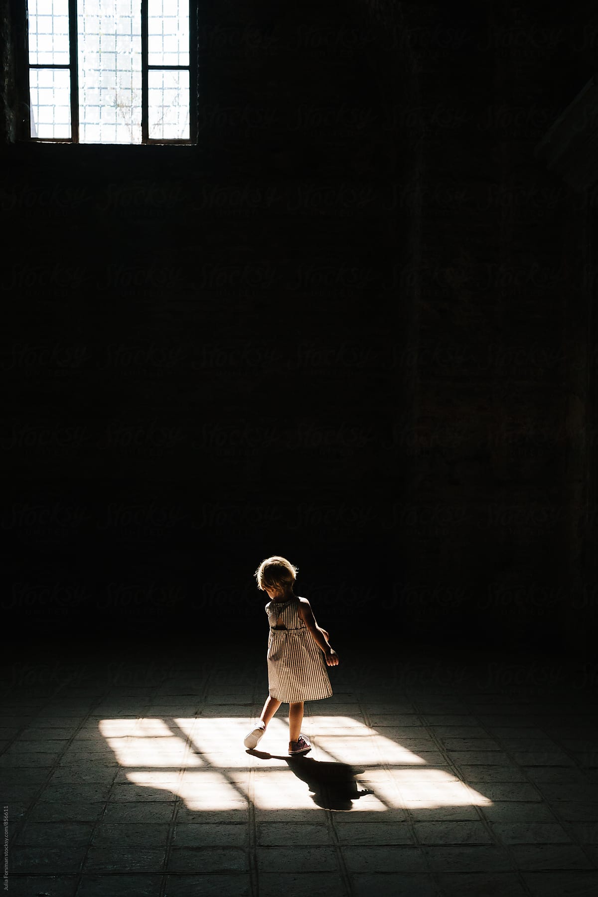 Back of little girl as she twirls in patch of light.