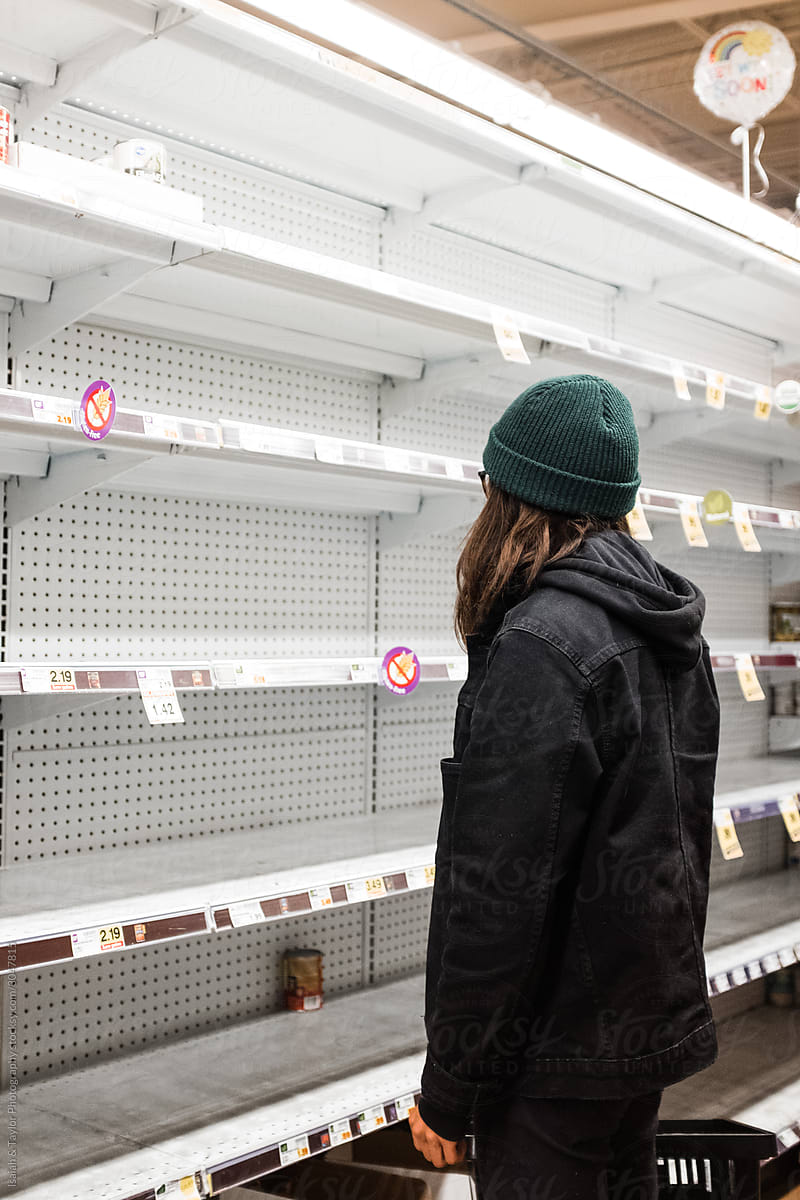Person confused staring at empty grocery store shelves during the Coronavirus pandemic
