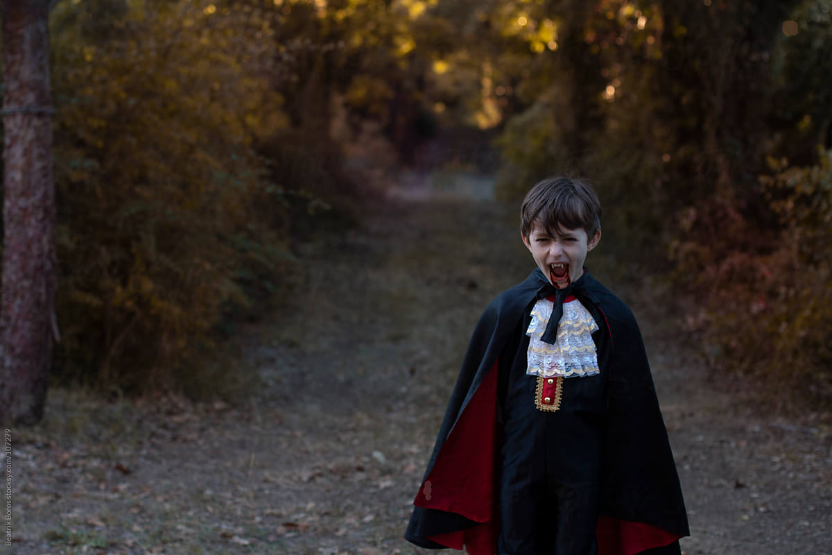 5 year old boy wearing Dracula costume in the forest
