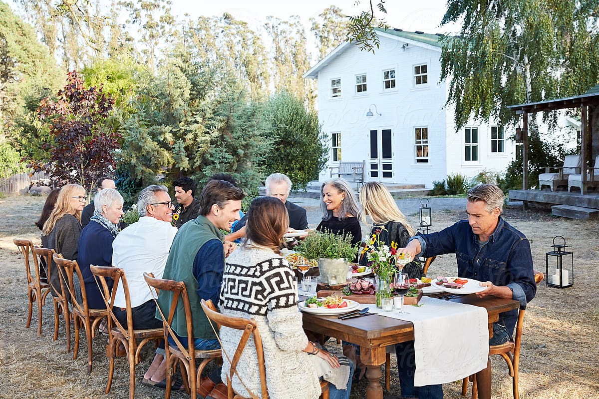 Group of friends having outdoor dinner party at farm