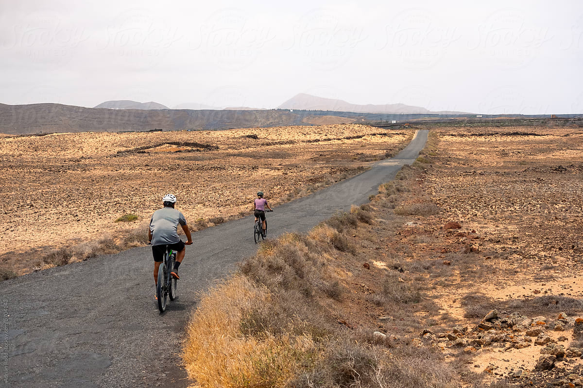 Two people riding bicycles explore the dry landscape of Lanzarote