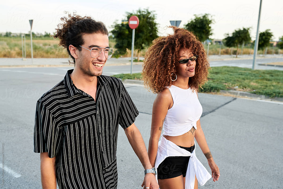 Stylish happy couple walking along the road.