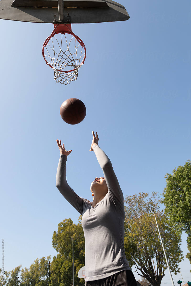 Teenage girl playing basketball on an outdoor court