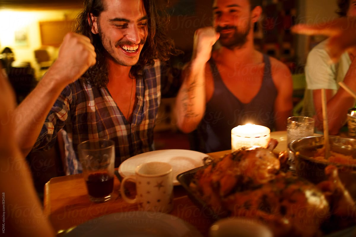 Friends sit around laughing and enjoying a dinner in candlelight.
