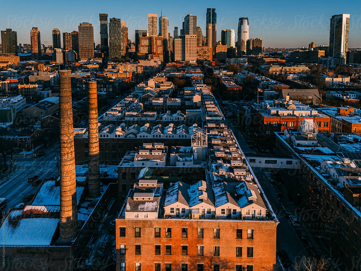 Sunset Glow on Rooftop Houses and Chimneys with Manhattan Skyline