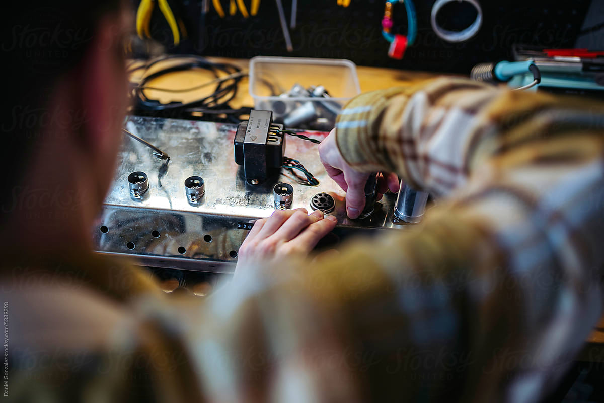 Repairman fixing amplifier in workshop