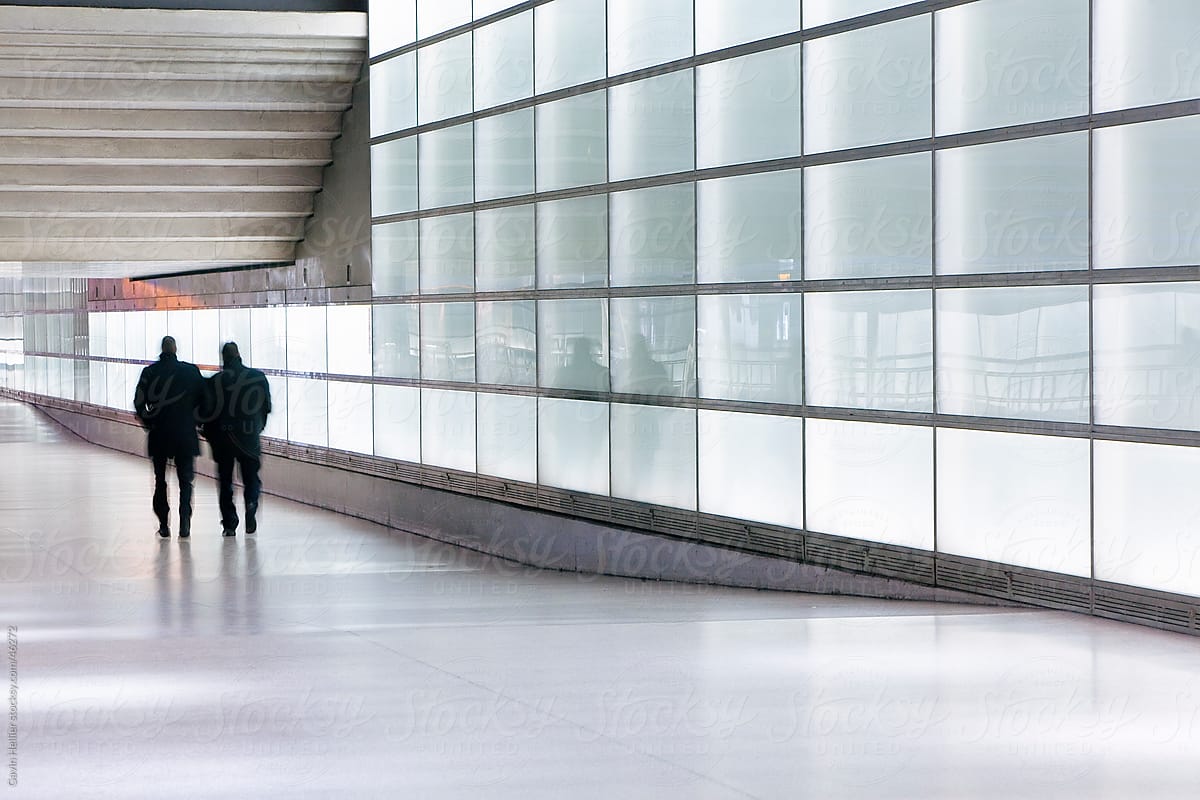 Europe, Germany, Berlin, glass walled passageway in modern building - people commuting - blurred motion