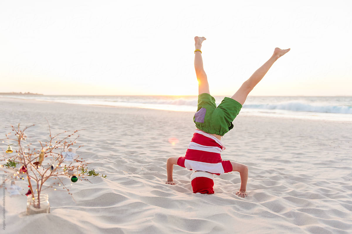 Child doing headstand at the beach at Christmas