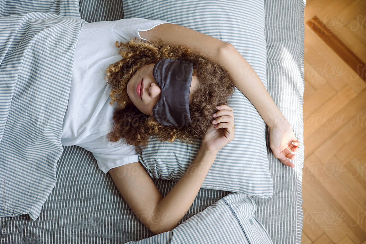 Portrait of a curly young woman in a sleep mask