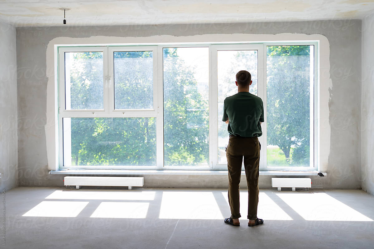 unrecognizable millennial man in front of window in a new empty home