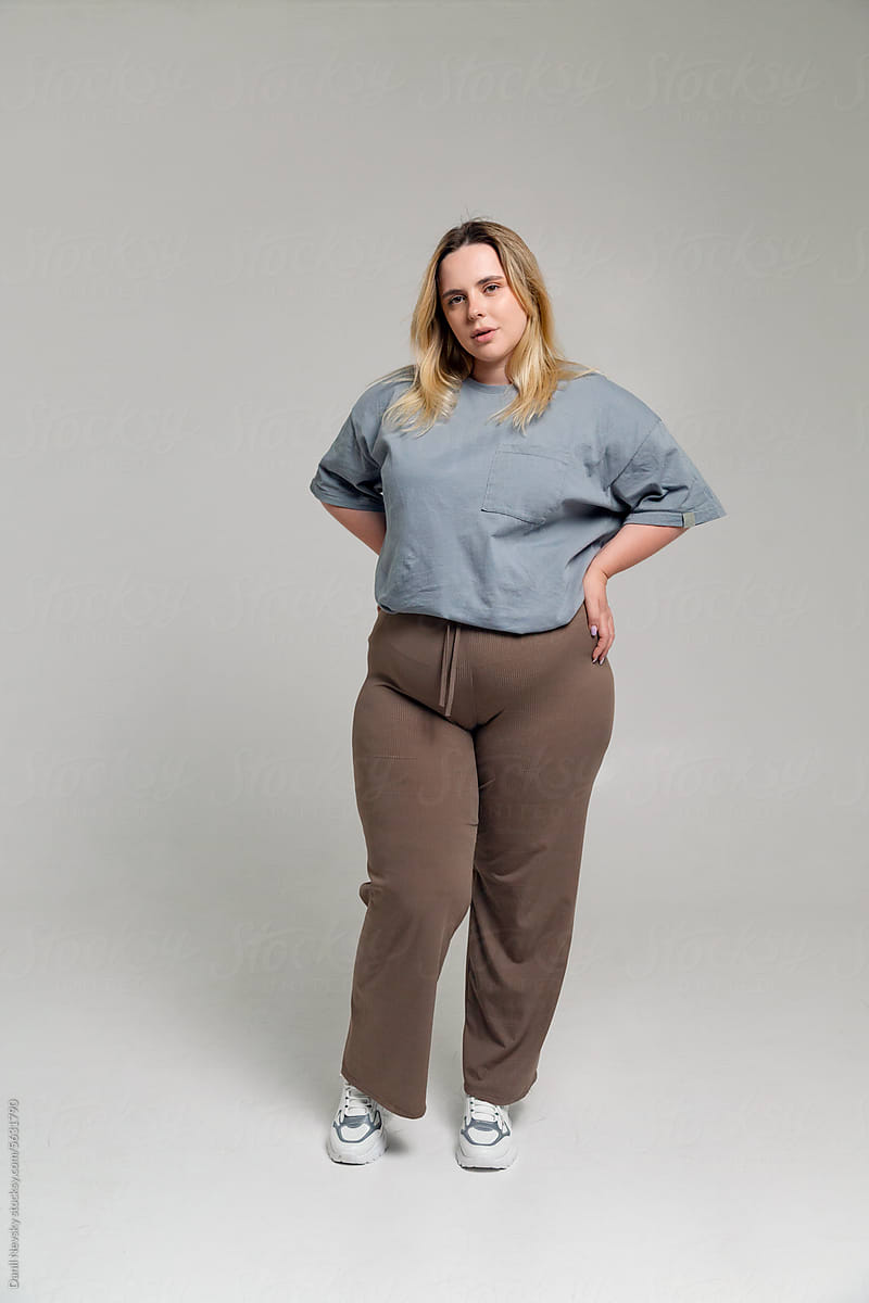 Happy young plus size woman standing with hands on waist