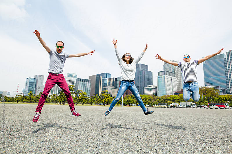 Portrait of young friends jumping in front of a Tokyo skyline.