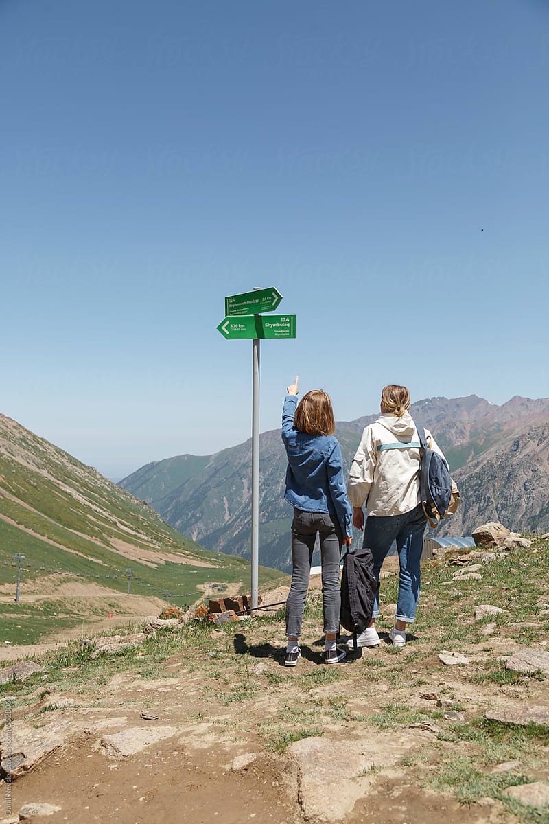 Traveling women near signpost in mountains