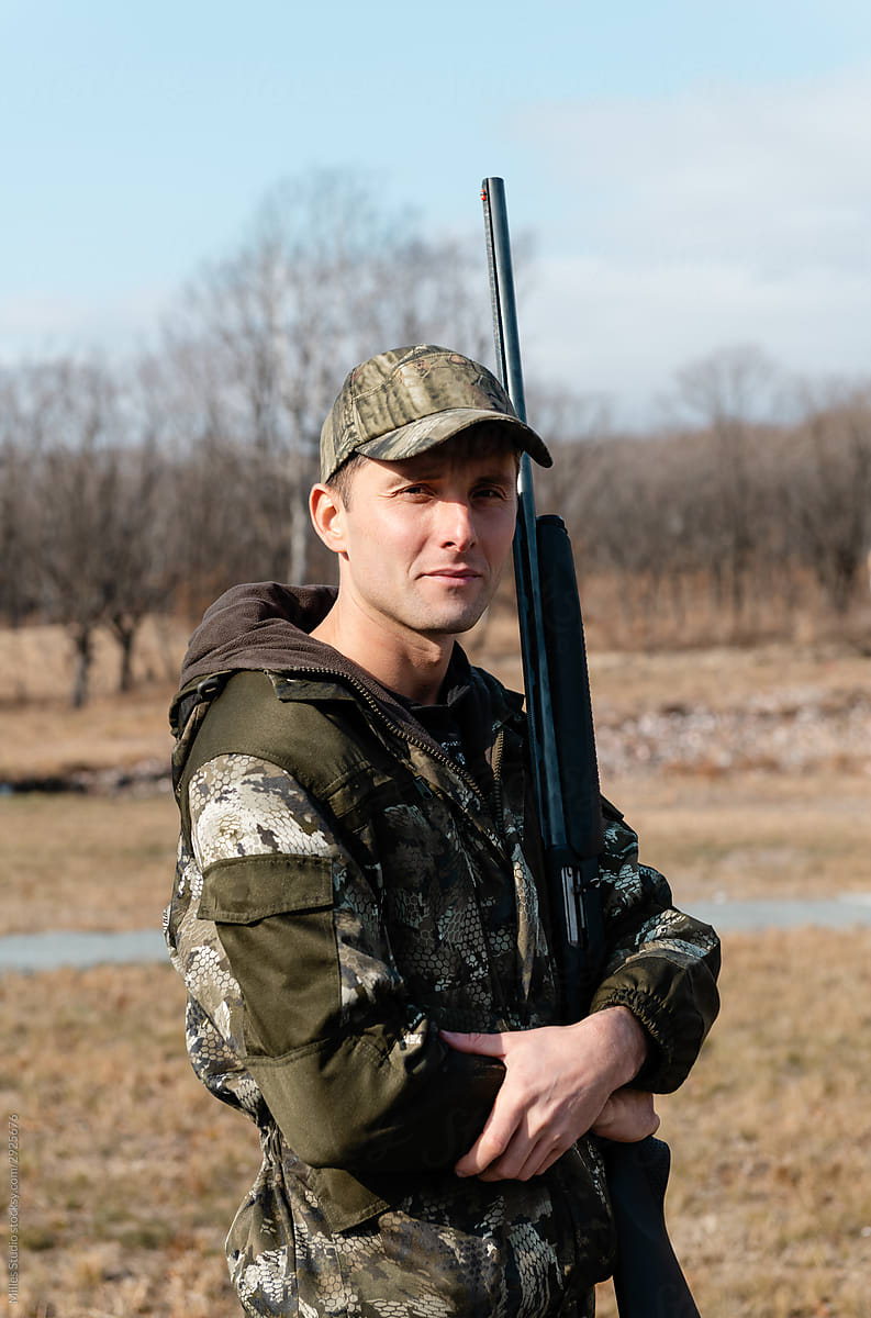 Hunter embracing gun in countryside