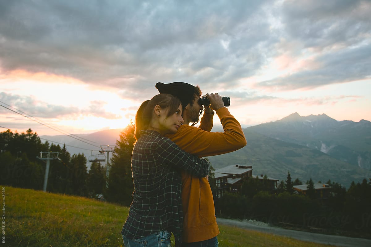 Woman embraced with man looking with binoculars. Beautiful landscape.