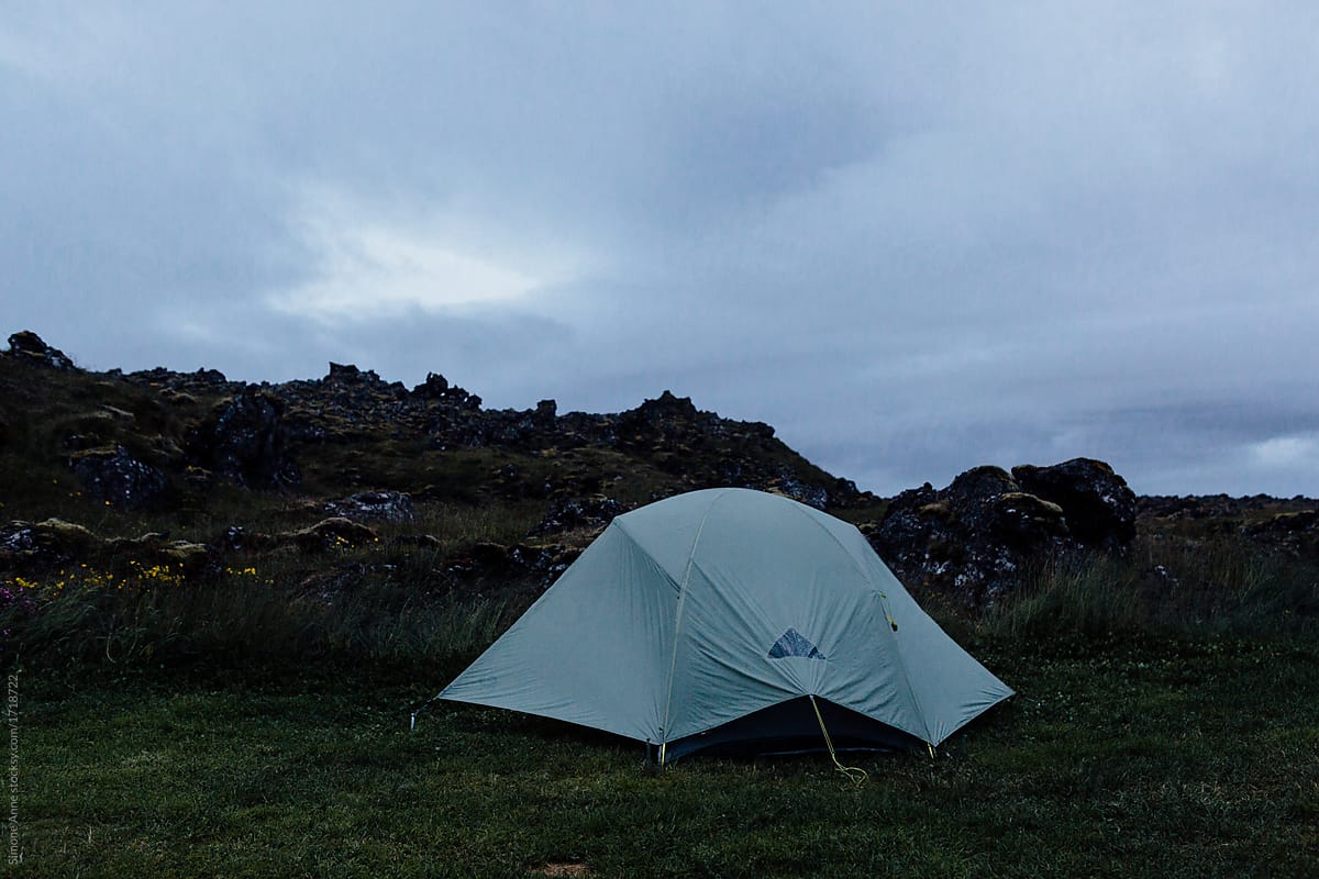 Camping tent set up in the rocks and volcanic land and greenery of Iceland