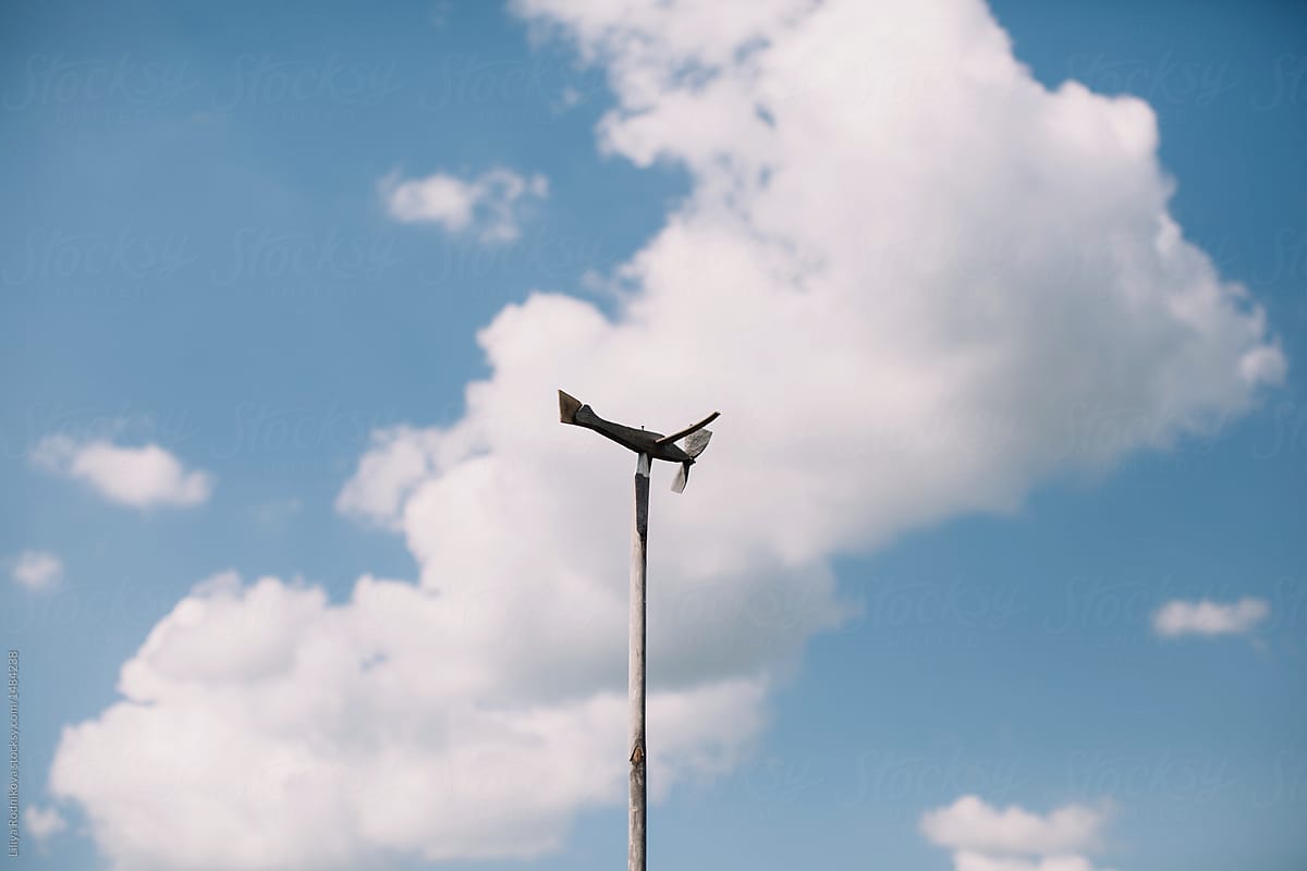 Airplane weather vane in front of cloudy sky