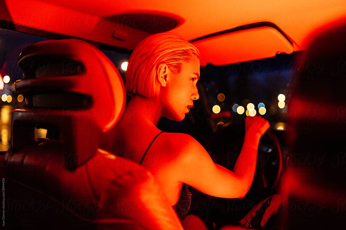 Mysterious woman in dark neon light in car